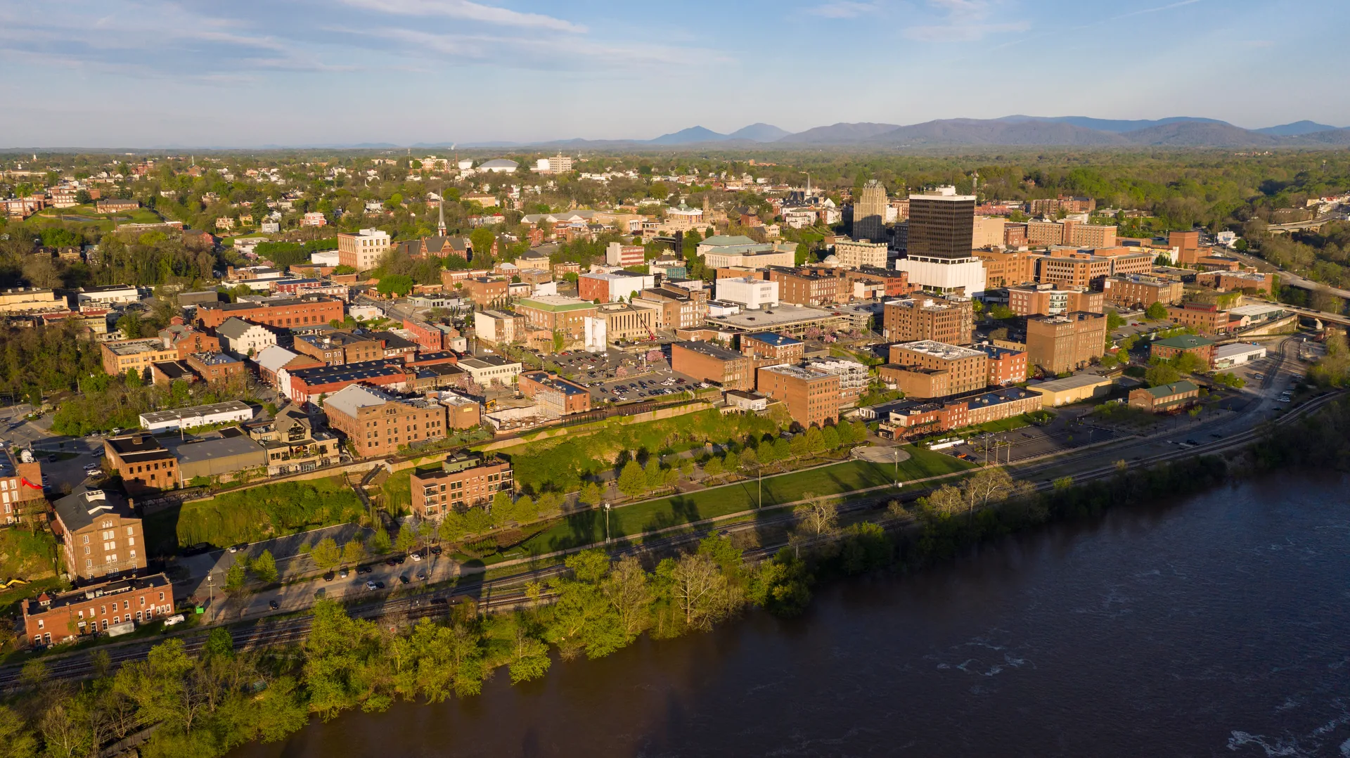 Aerial view of Lynchburg, VA skyline showcasing downtown buildings, green spaces, and the James River.